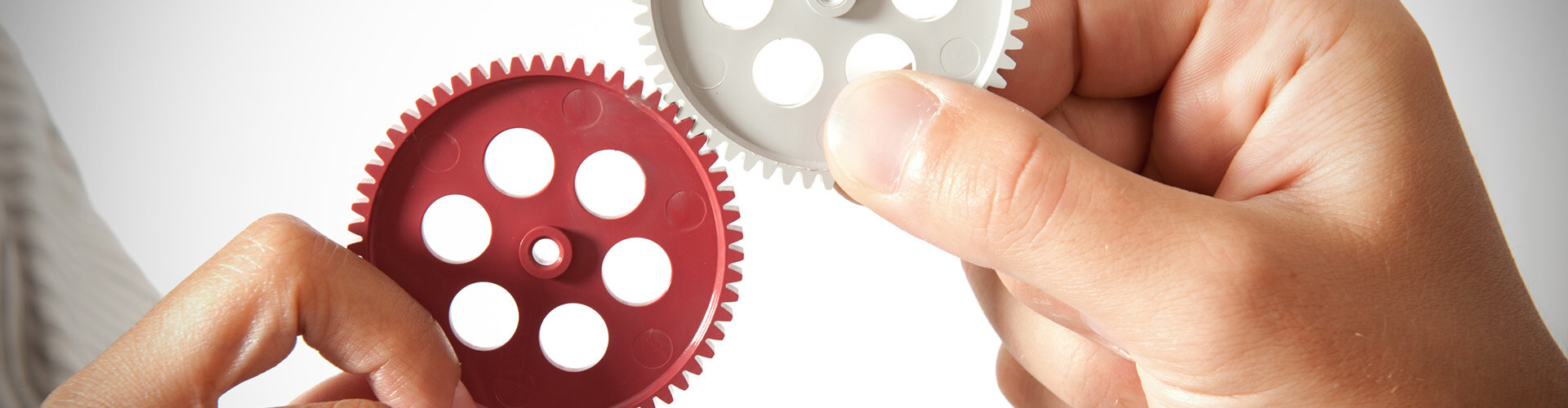 Zwei Hände halten Zahnräder ineinander