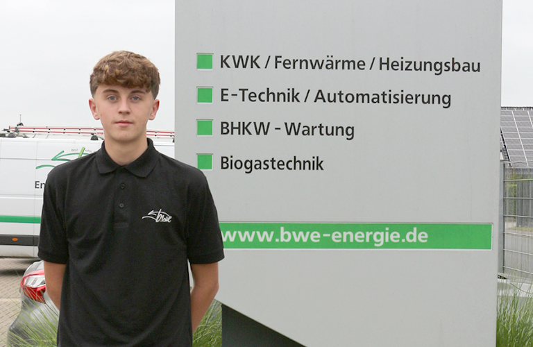Auszubildender Industriekaufmann vor einem Schild